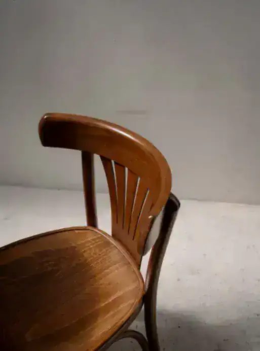 Vintage wooden dining chair with curved backrest and slatted design.