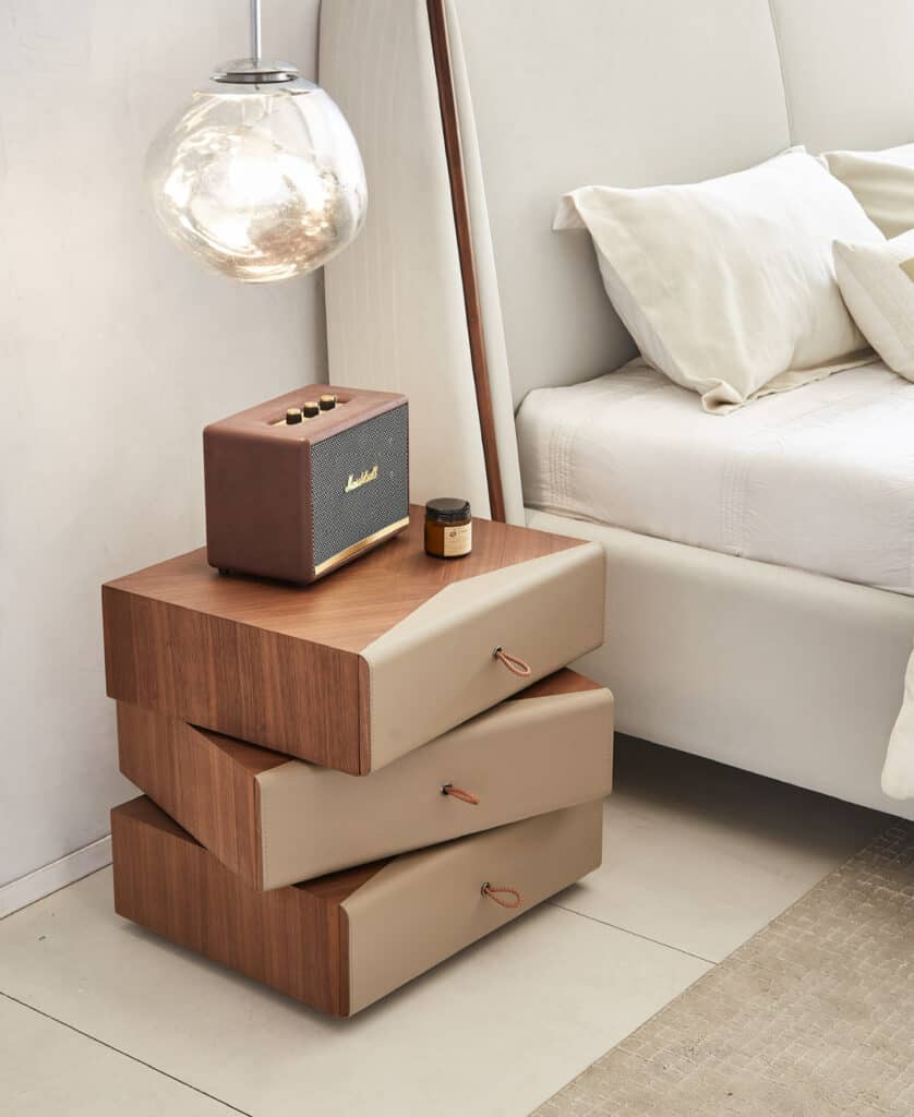 Stylish bedroom nightstand with storage drawers, a vintage speaker, and a bedside lamp.