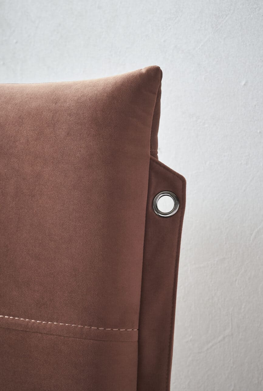 Close-up of a plush, rust-colored velvet accent chair for stylish home decor.