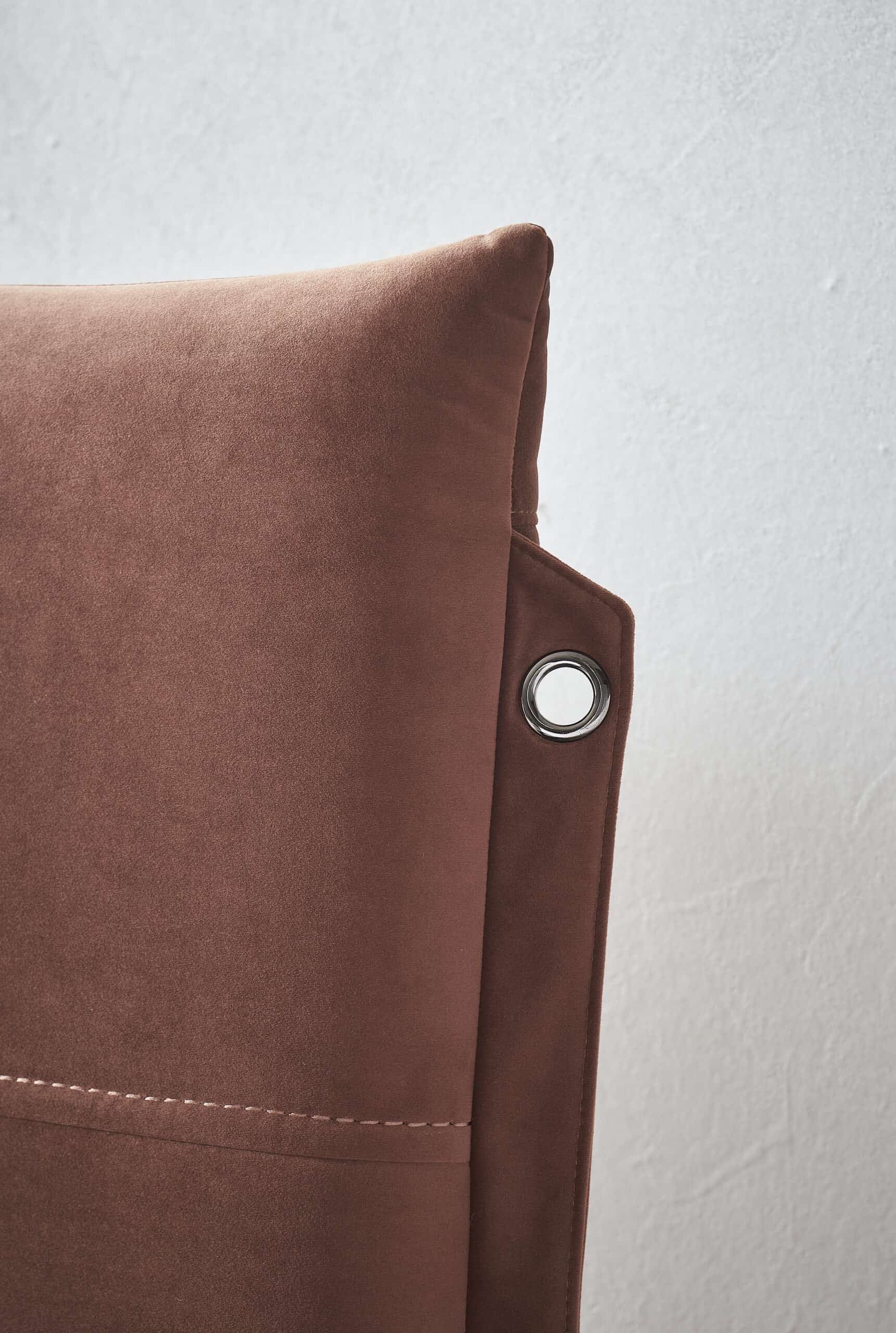 Close-up of a plush, rust-colored velvet accent chair for stylish home decor.