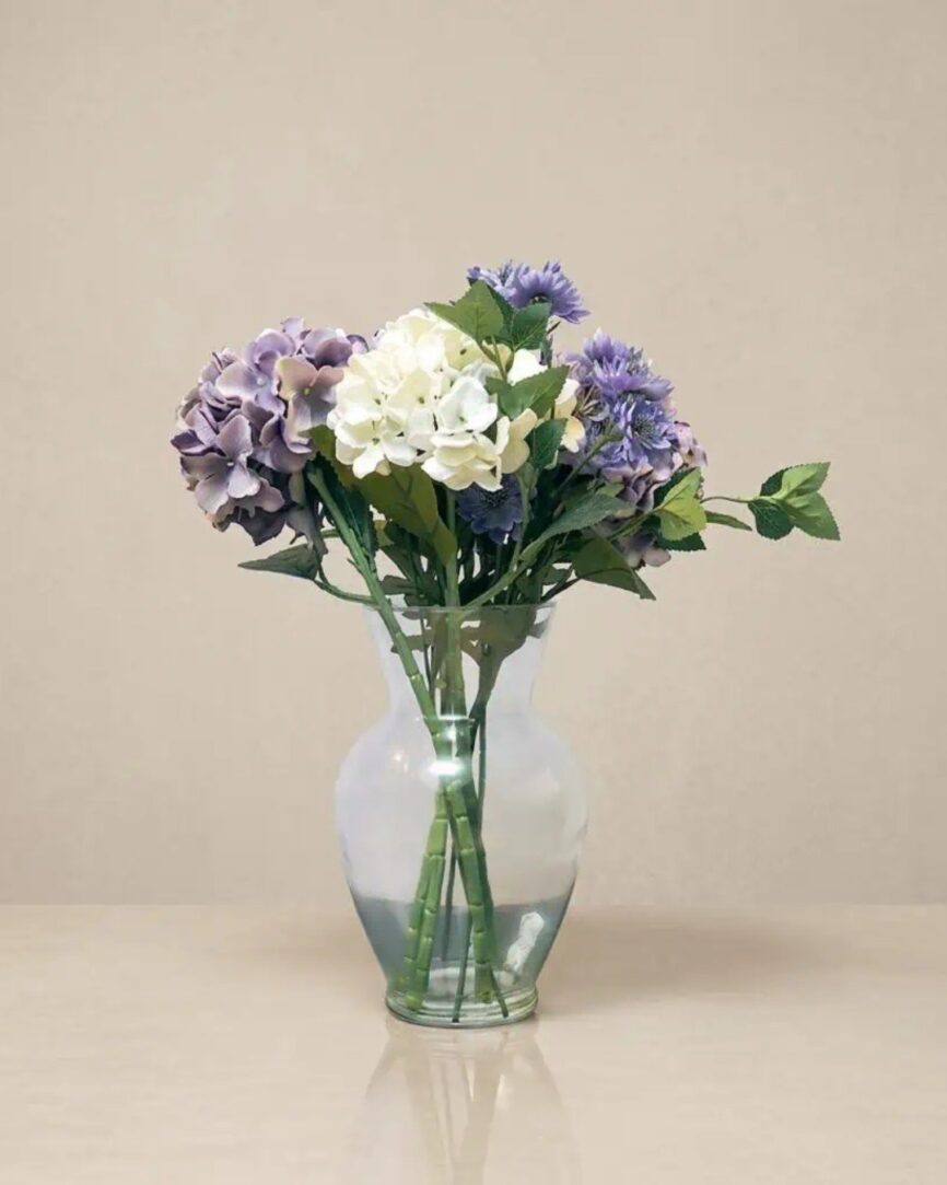 Hydrangea flower bouquet in a clear glass vase, decorative home floral arrangement.