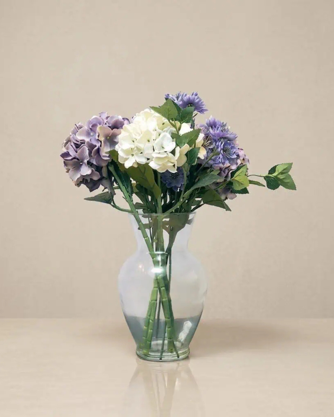 Hydrangea flower bouquet in a clear glass vase, decorative home floral arrangement.