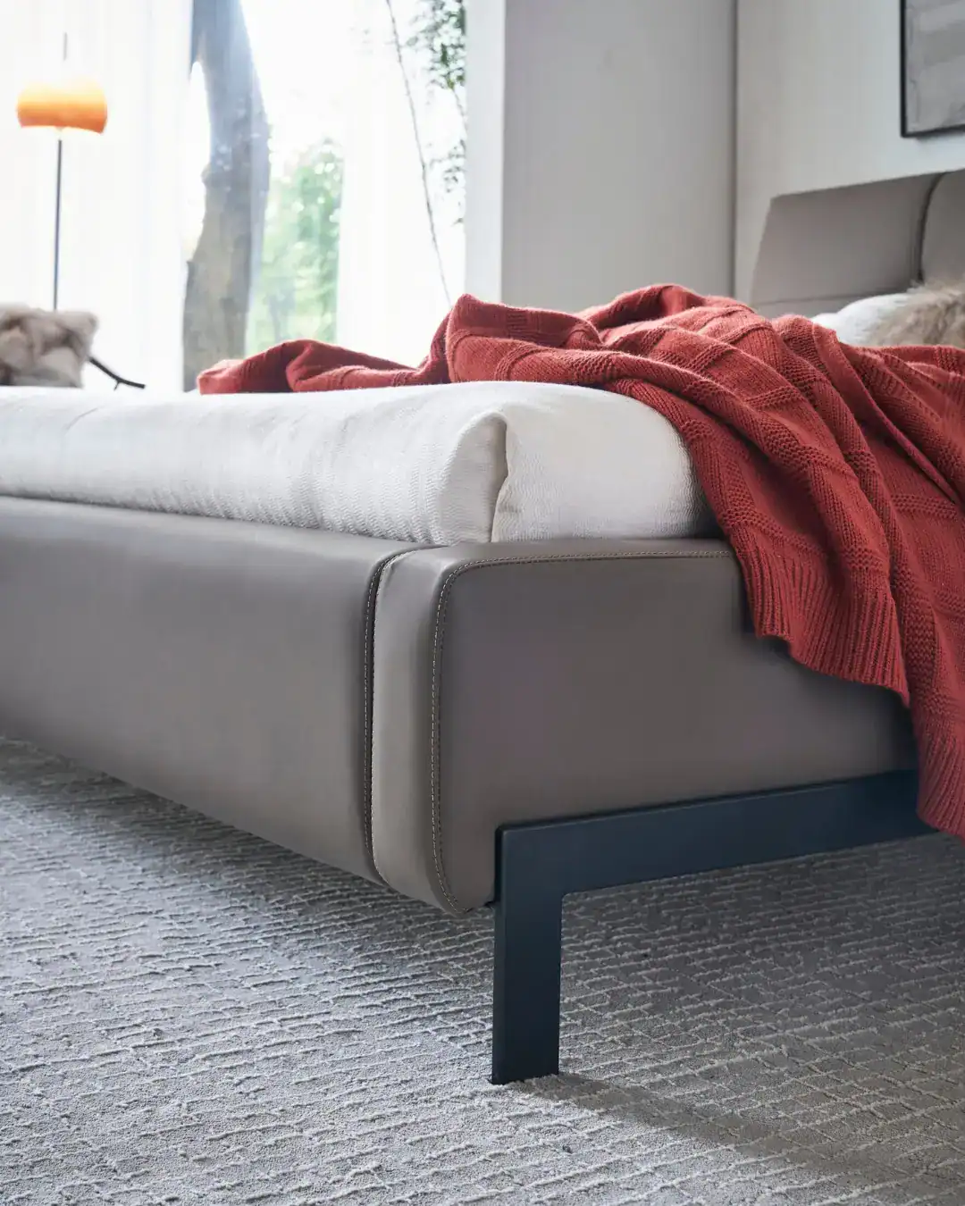 Elegant Dainty Bed with neutral tones and cozy red throw blanket in modern bedroom setting.