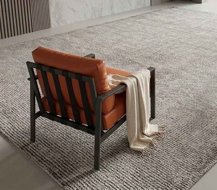 A comfortable leather armchair with a black wooden frame and a beige throw blanket, placed on a text.
