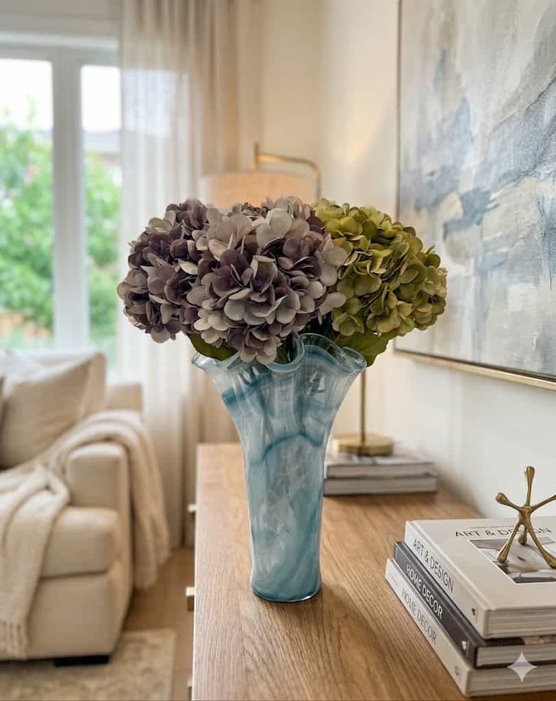 Elegant hydrangea stem flower arrangement in a blue glass vase, perfect for home decor.