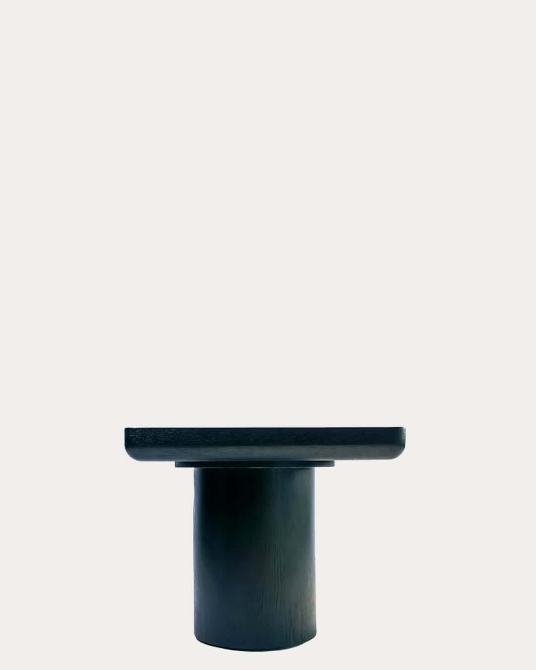 Modern black table with cylindrical base, perfect for contemporary home decor.