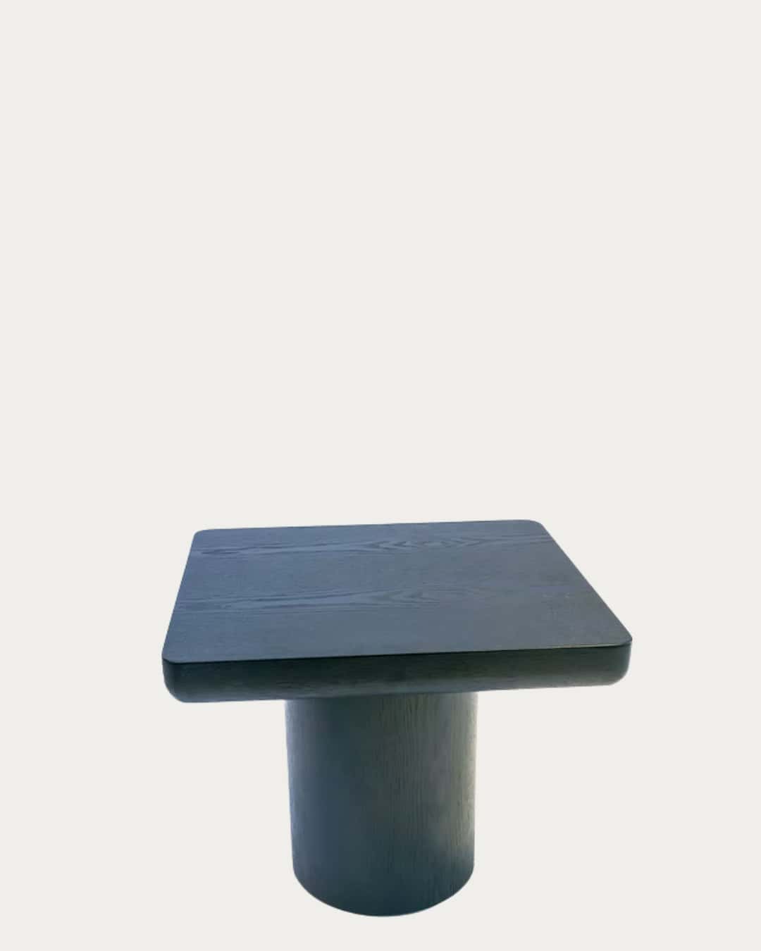 Black wooden table with a cylindrical base, modern and minimalist design for living room or office.