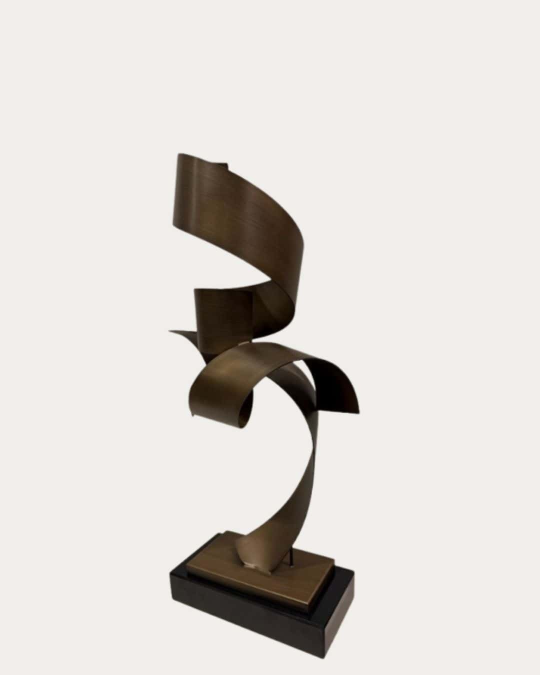 Bronze spiral metal ornament on black marble base, modern decorative sculpture.