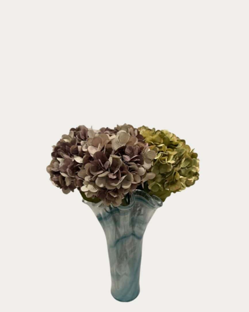 Hydrangea stem flower arrangement in a blue ceramic vase, perfect for home decor.